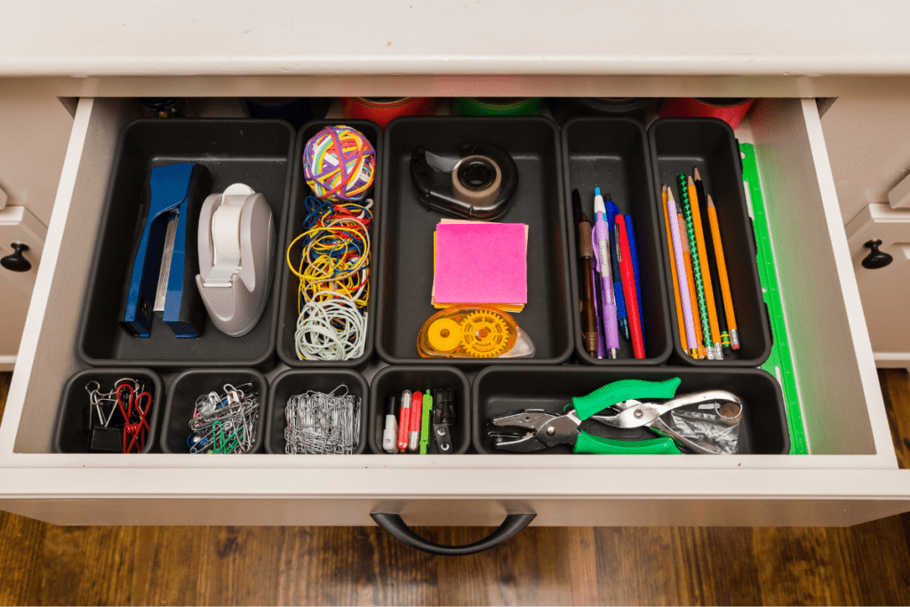 Drawer containing a drawer organizer to keep office supplies in their proper place such as hole punchers, tape, pens, pencils, and paper clips.