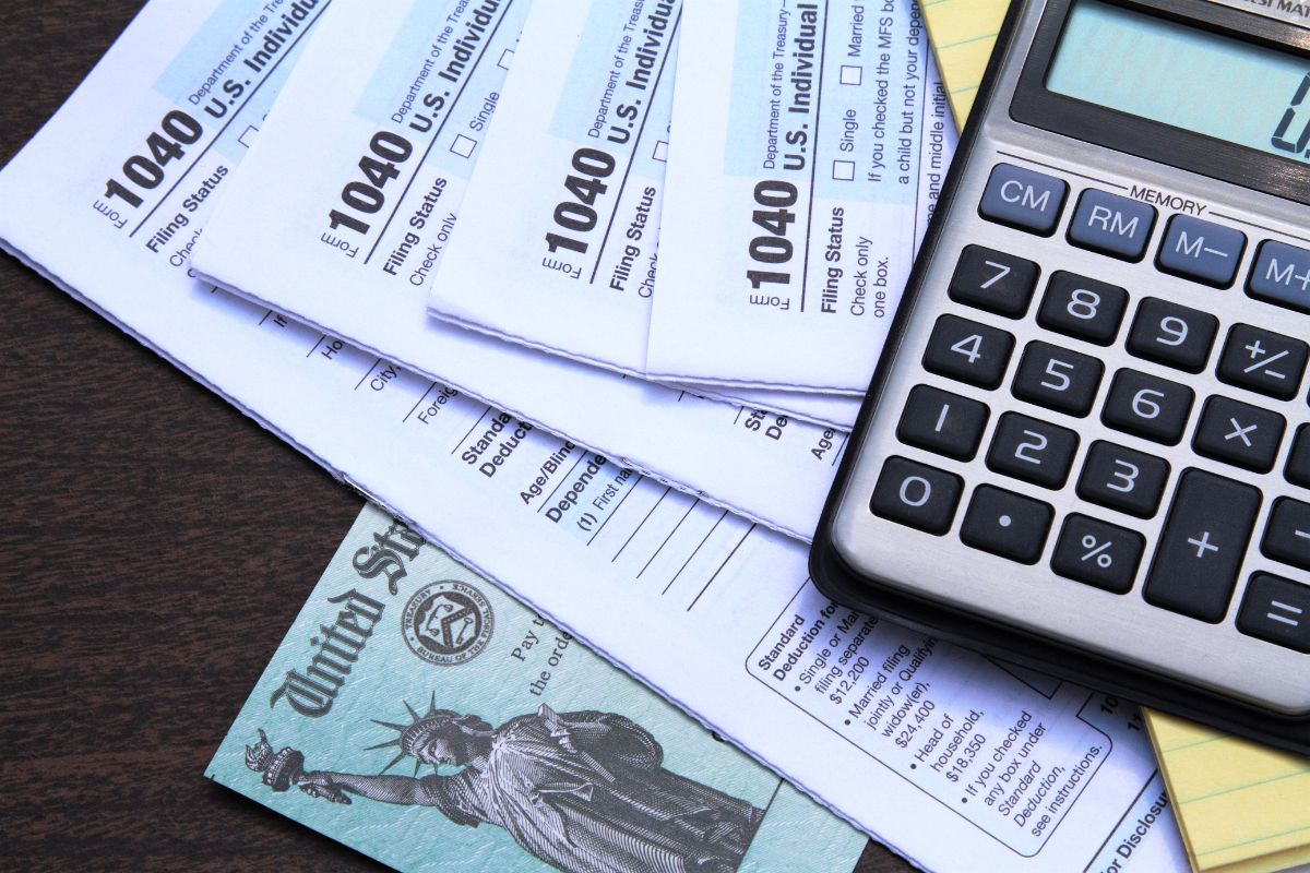 A stack of 1040 tax forms fanned out under a calculator.