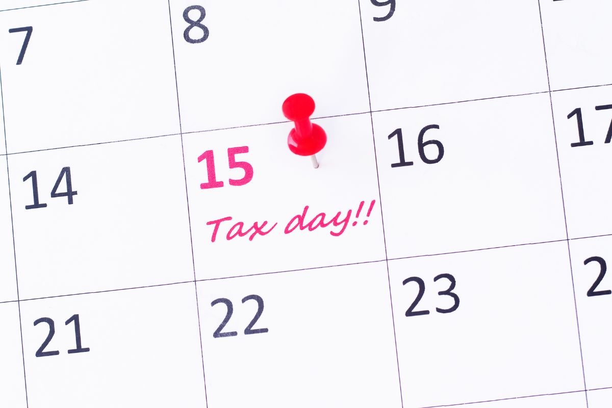 A black and white plain calendar with "Tax day!!!" written in red ink on the 15th's box.