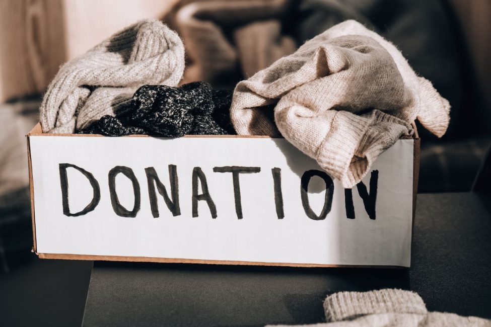 A box labeled "DONATION" overflowing with clothing items.