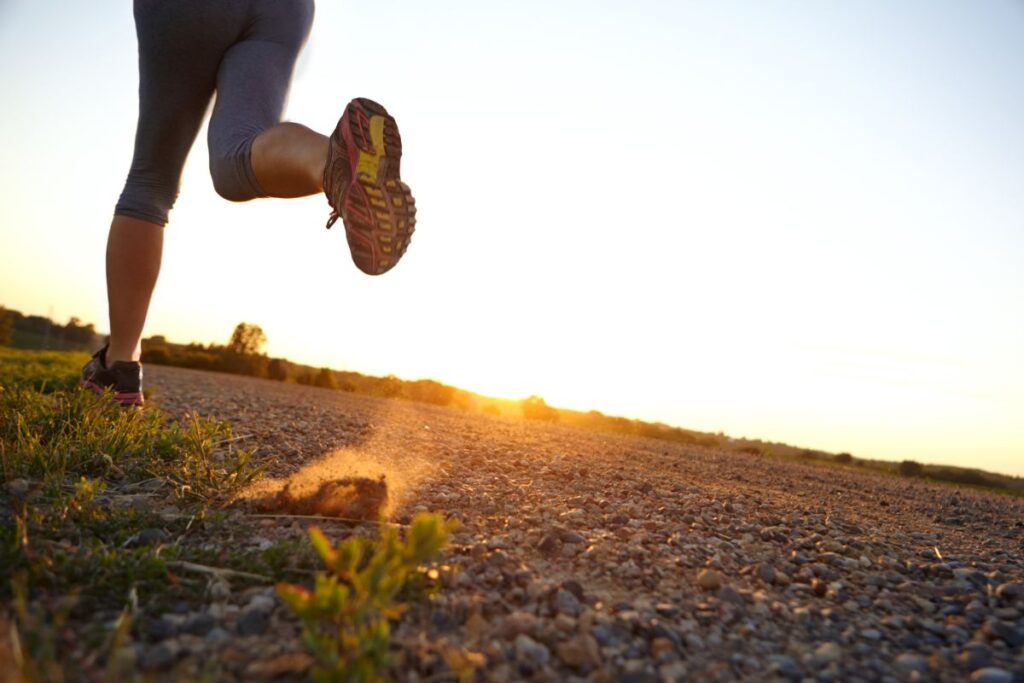A woman running outdoors with the sun setting in the background. 