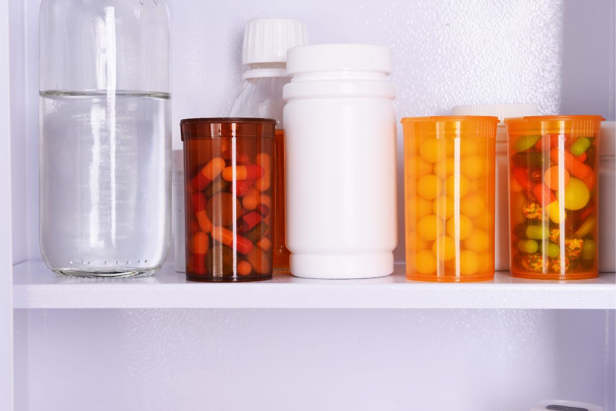 An open medicine cabinet with bottles of pills and other medicines lined up neatly.