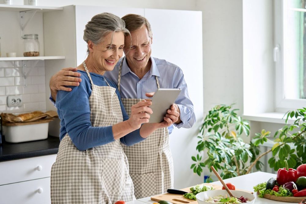 couple in aprons cooking with tablet