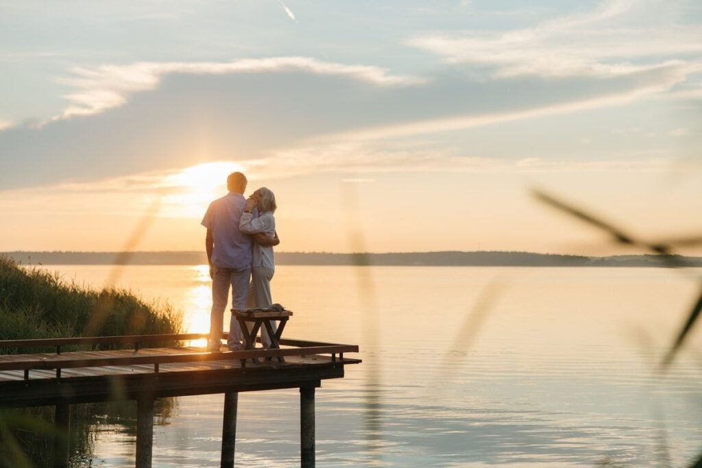 Man and Woman Sitting on Wooden Dock during Sunset