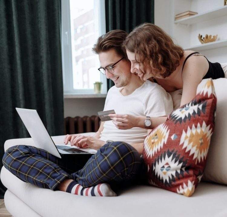 man and woman sitting on couch shopping online