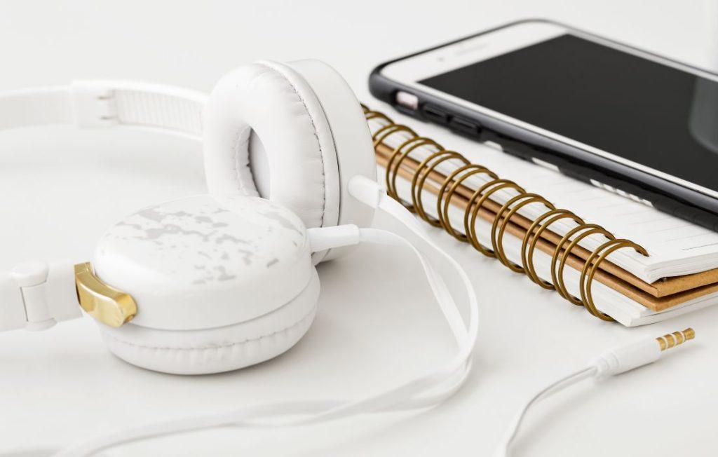 white headphones smartphone notebook on white desk