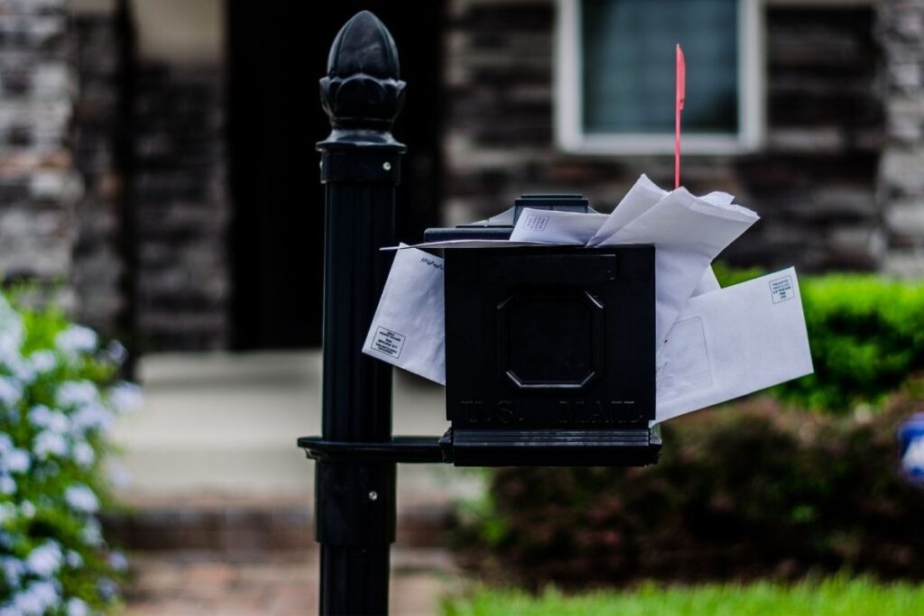 Black mailbox overflowing with junk mail
