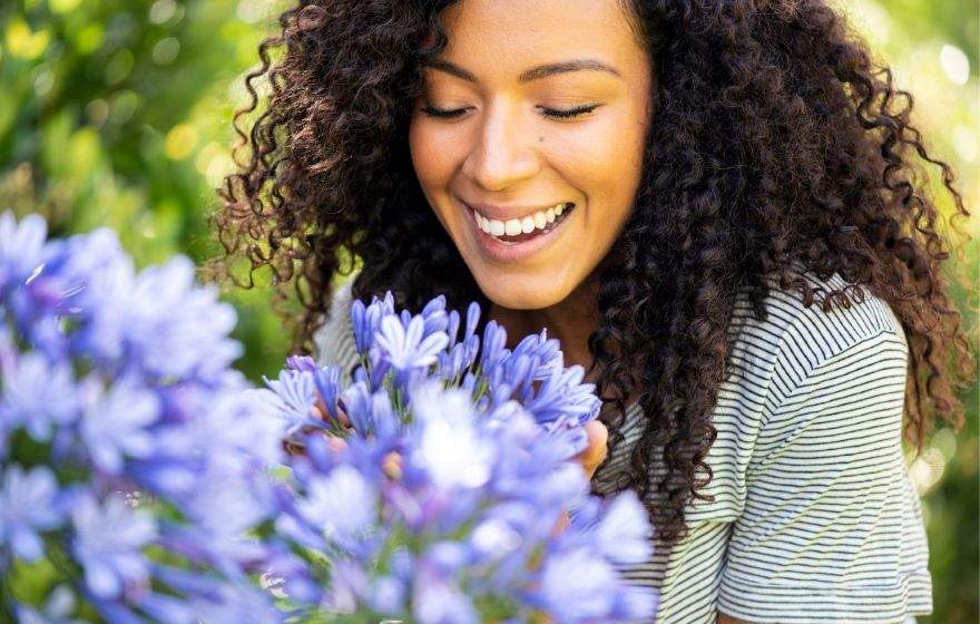 smiling woman smelling flowers