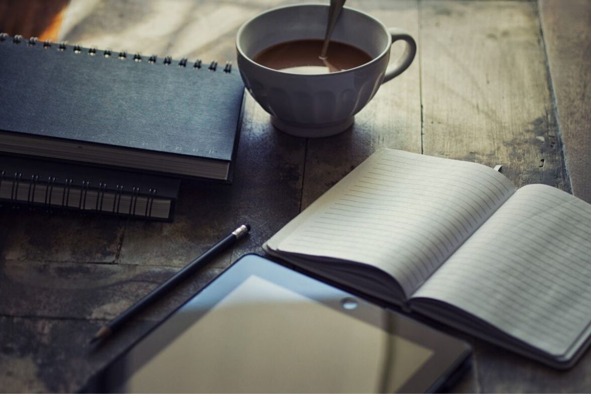 Cup filled with Coffee Near Journal and Tablet
