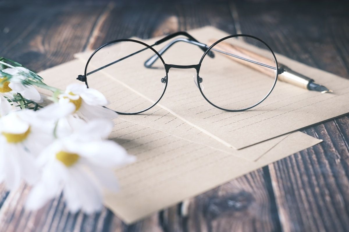 Round Eyeglasses Lined Paper and Daisies on Wood desk