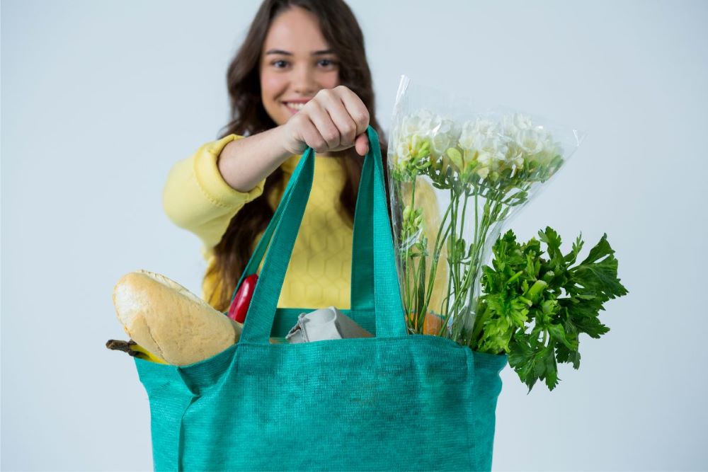 Young woman holding bag full of groceries