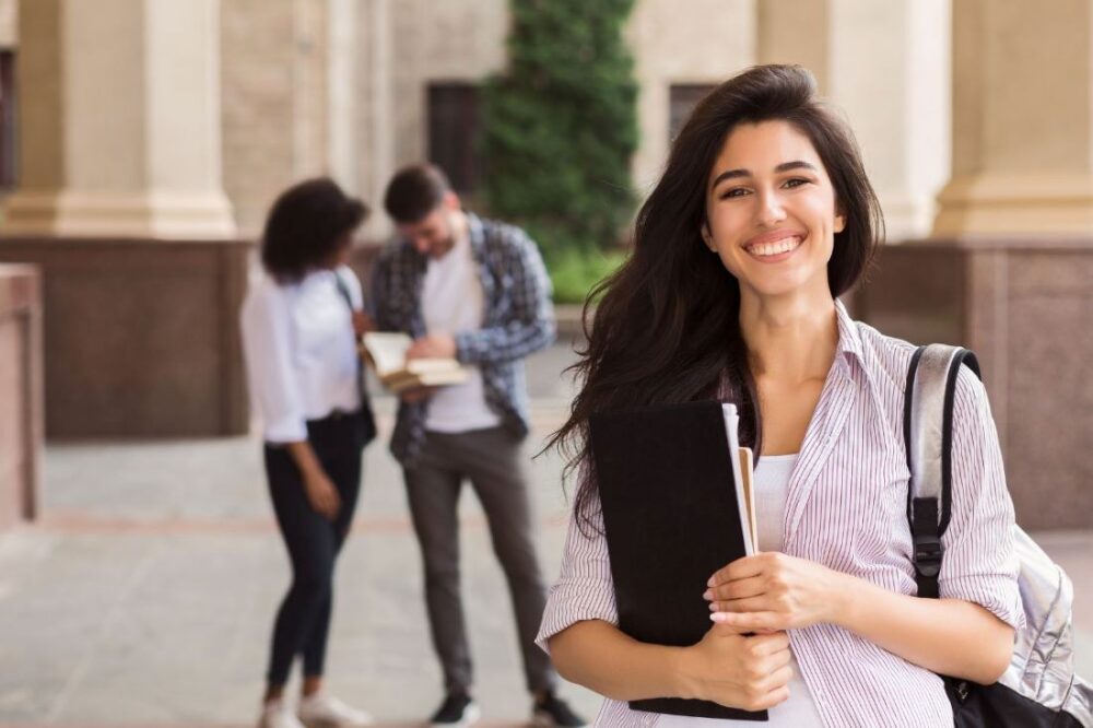 smiling young college student holding books