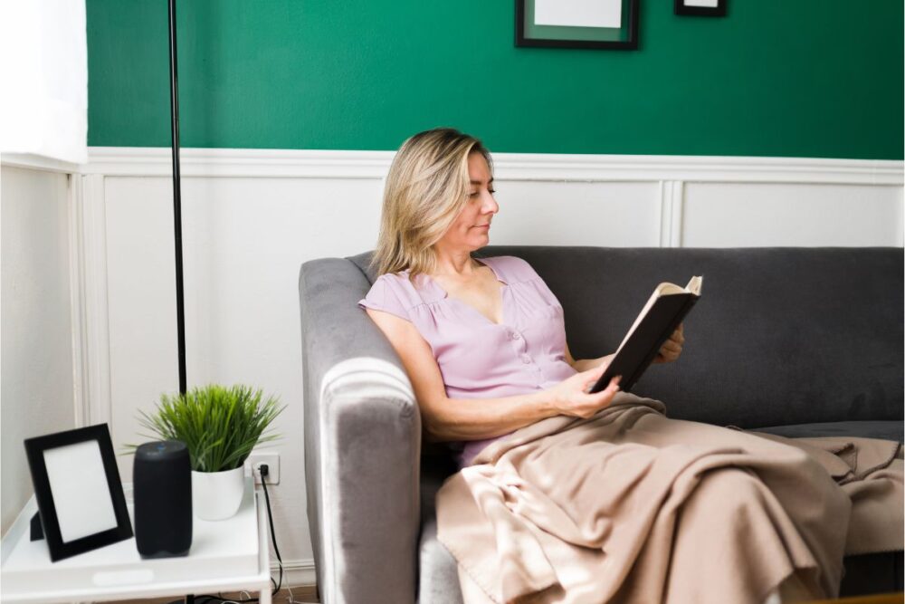 A woman sitting on a couch in a living room reading a book.