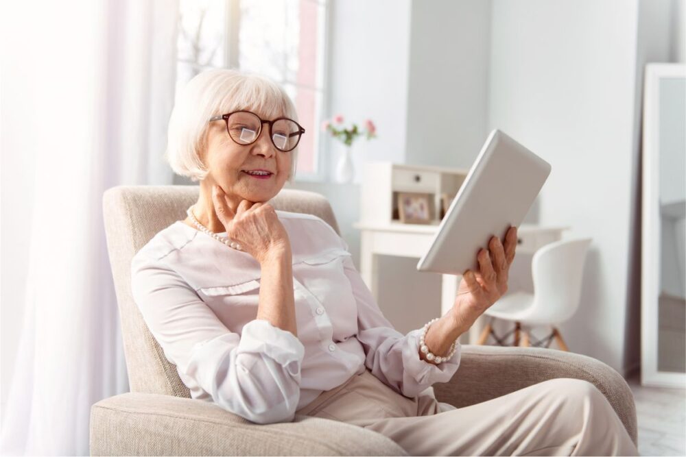 Happy older adult woman reading tablet