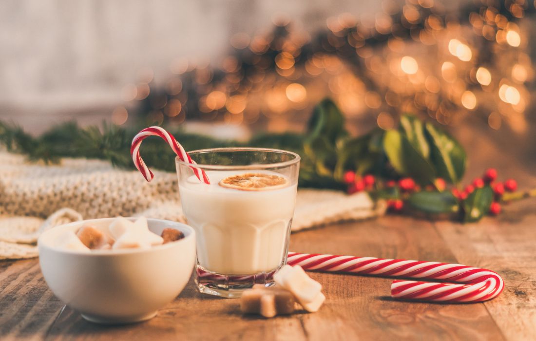 Holiday glasses with peppermints and wreaths in the background.