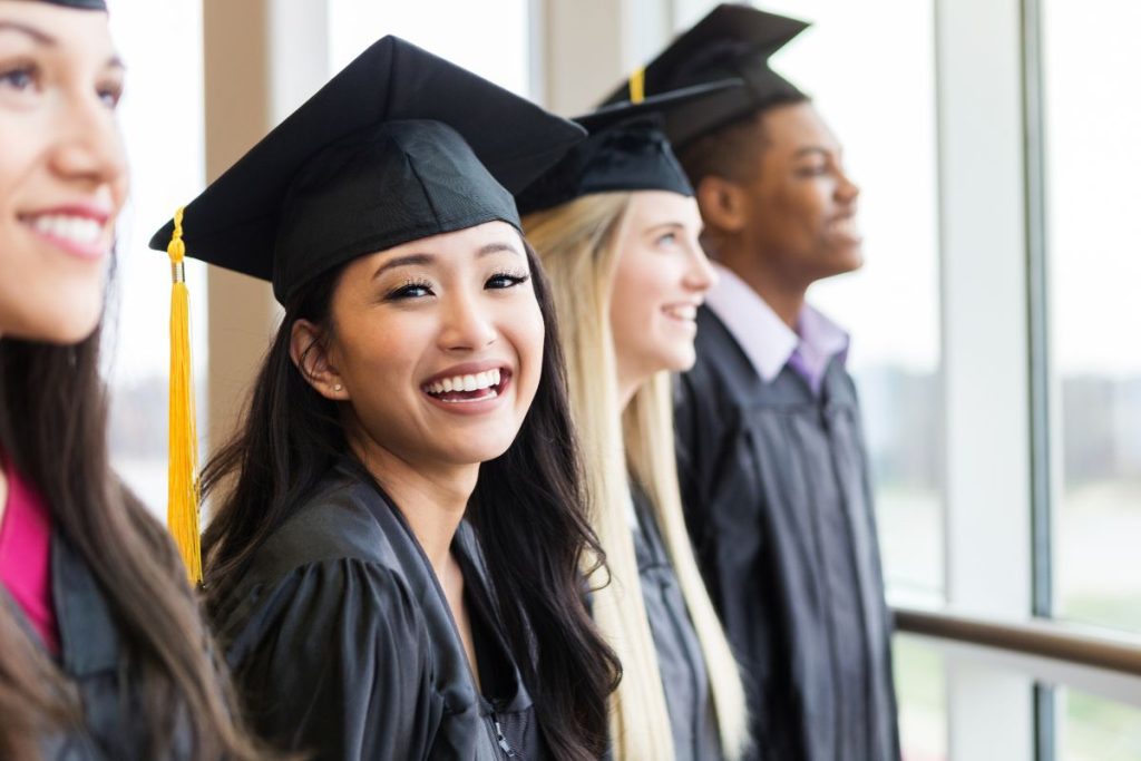 smiling young adult cap gown at graduation ceremony