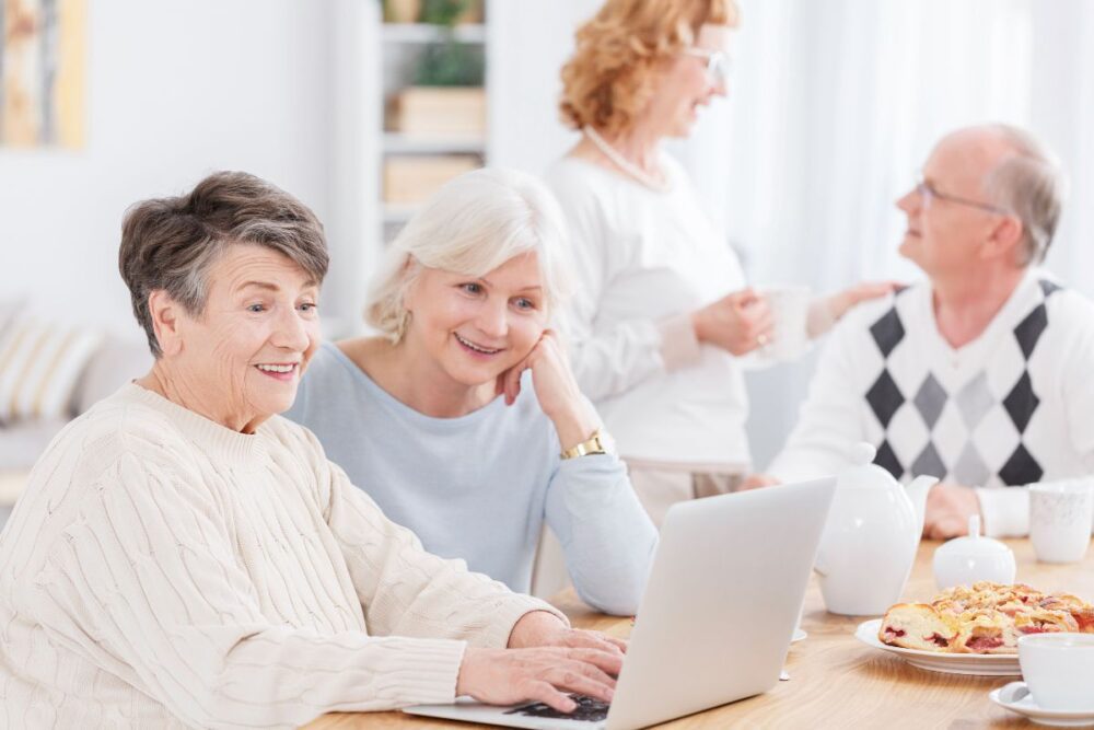 two senior women using a computer at gathering