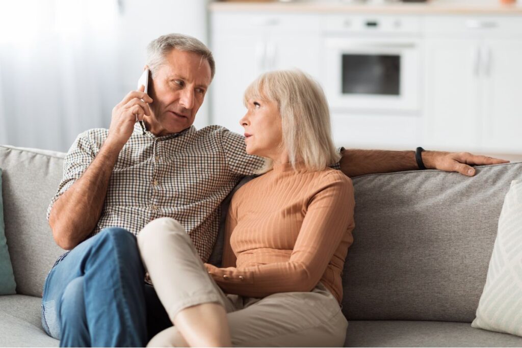 Older couple on a couch looking concerned during an unexpected phone call